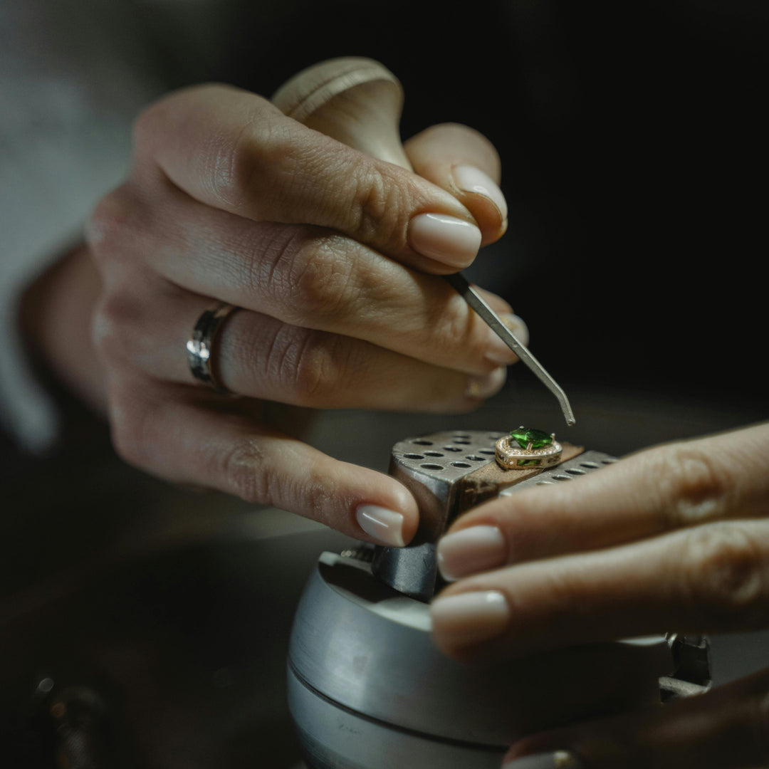 Close-up of hands working on setting diamonds in jewellery with a dark background