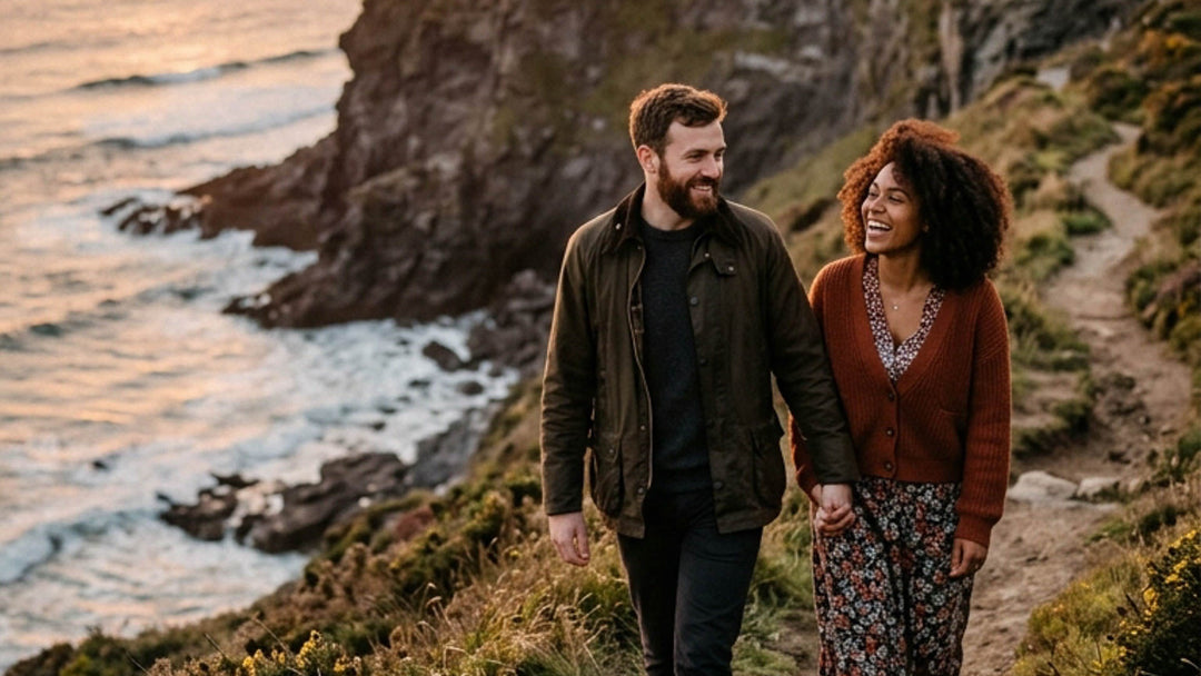 Couple on a cliffside walk by the beach after a destination proposal with a placeholder engagement ring