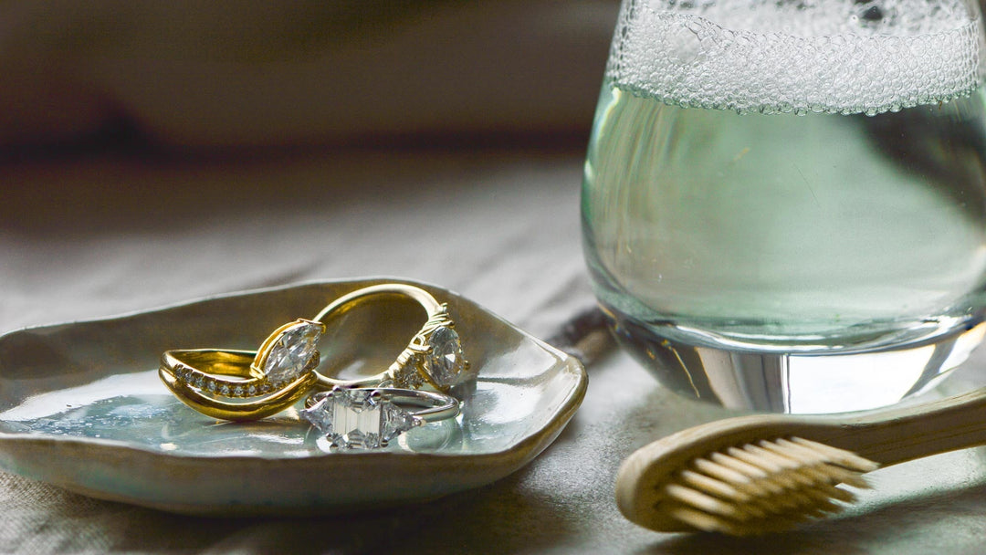 Collection of rings next to a glass of soapy liquid and a toothbrush