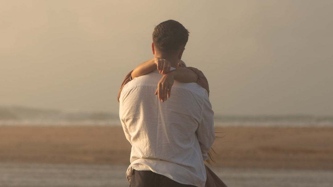 A couple embrace on a Cornish beach at sunset