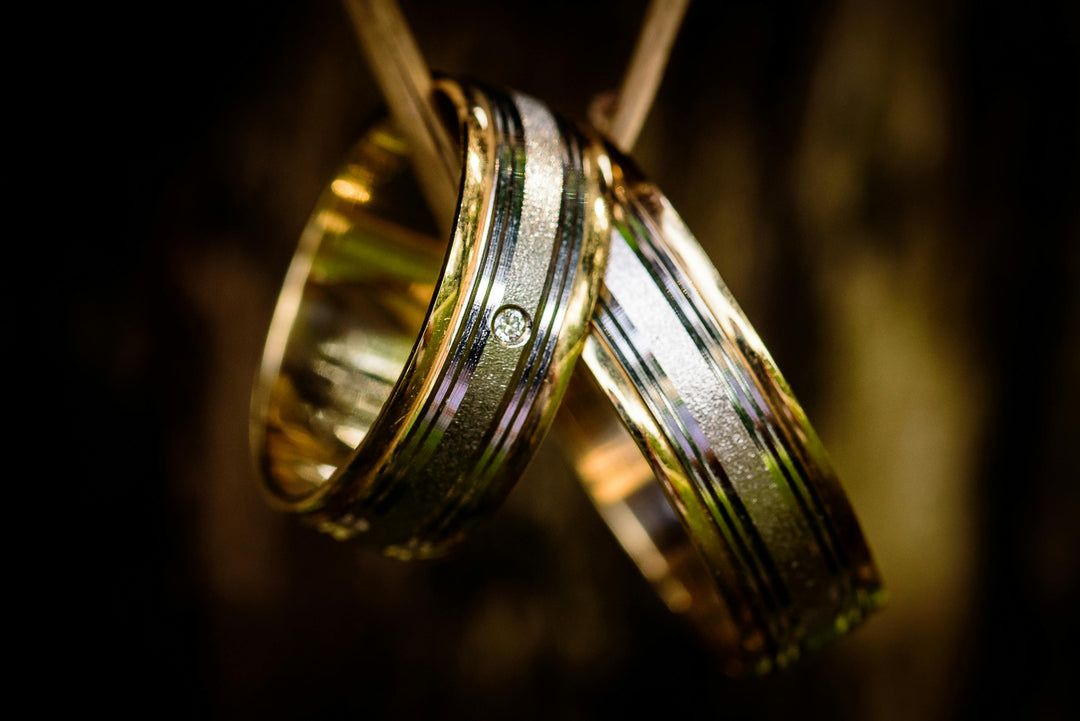 Two mixed metal gold wedding bands hang on a simple cord with a blurred background