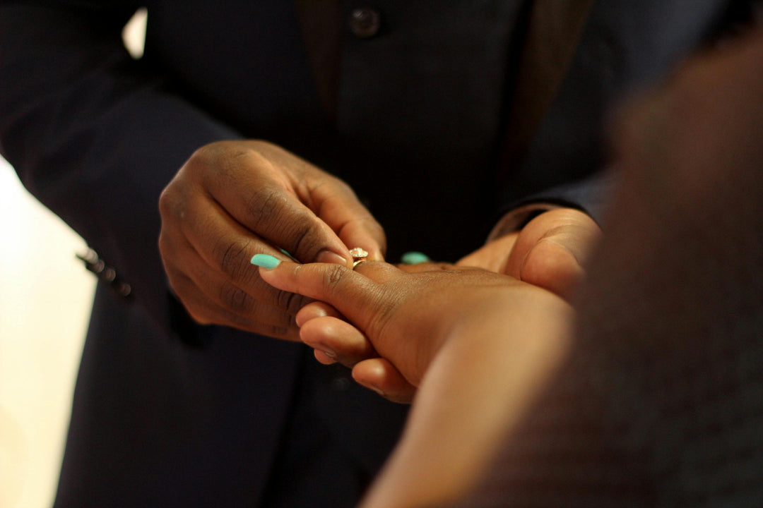 A man places an engagement ring on a woman's finger