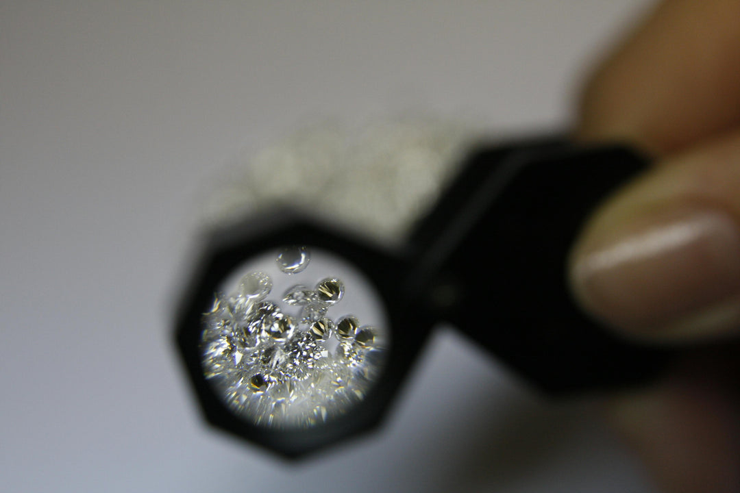 Magnified diamonds under a jewellers loupe on a white background