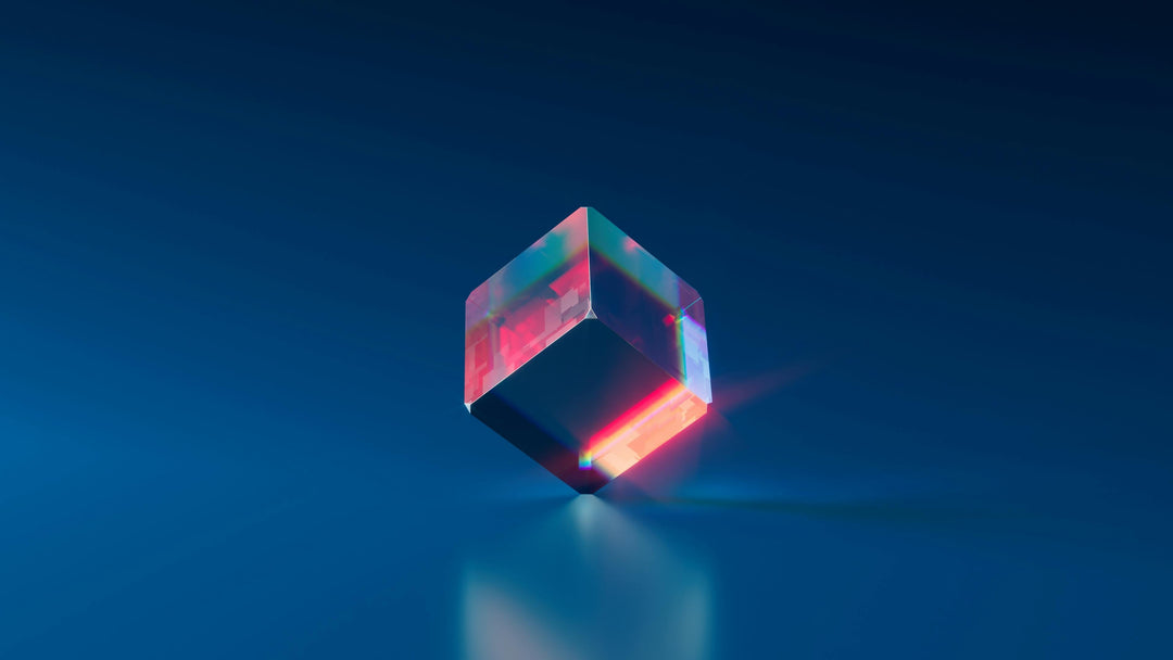 A transparent cube refracts light, creating a rainbow through the cube