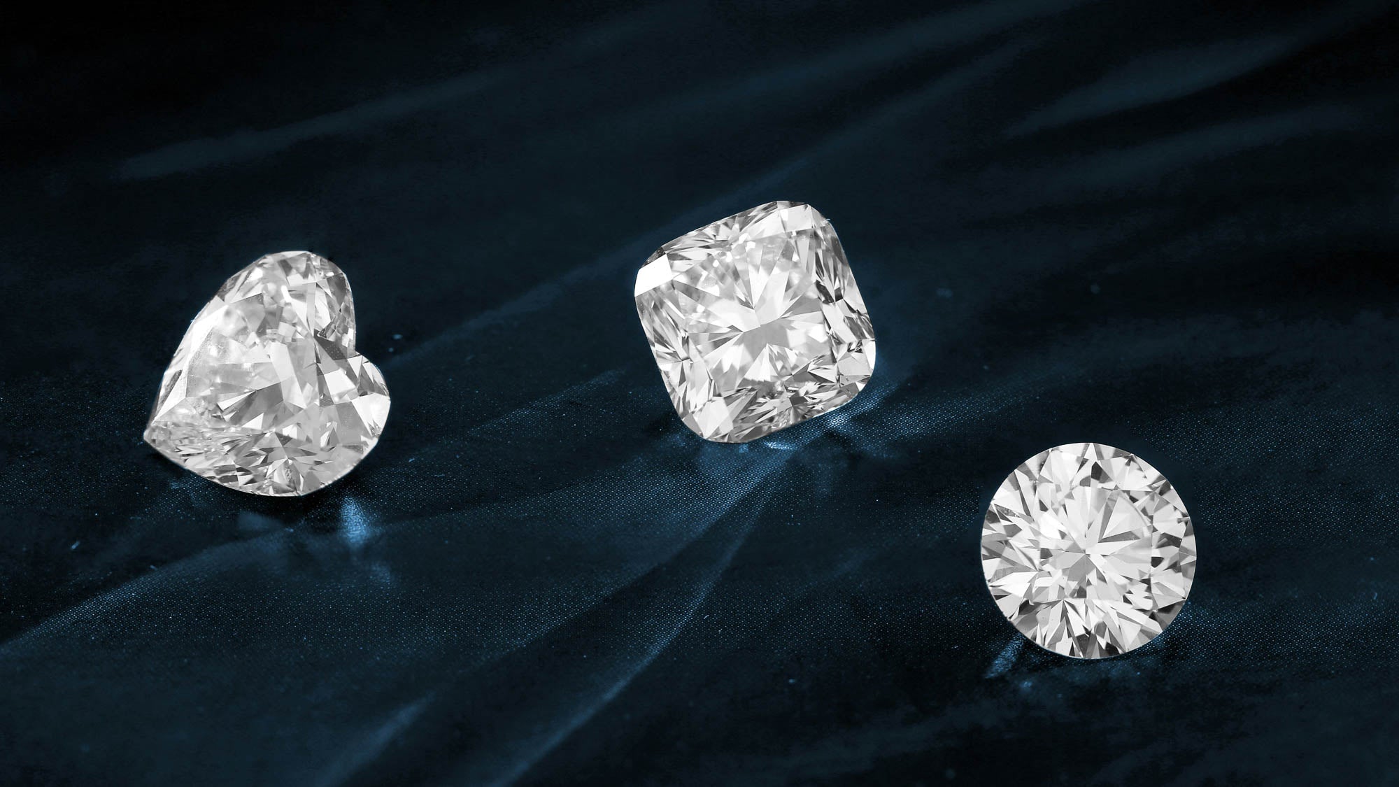 Three different cut diamonds on blue velvet background