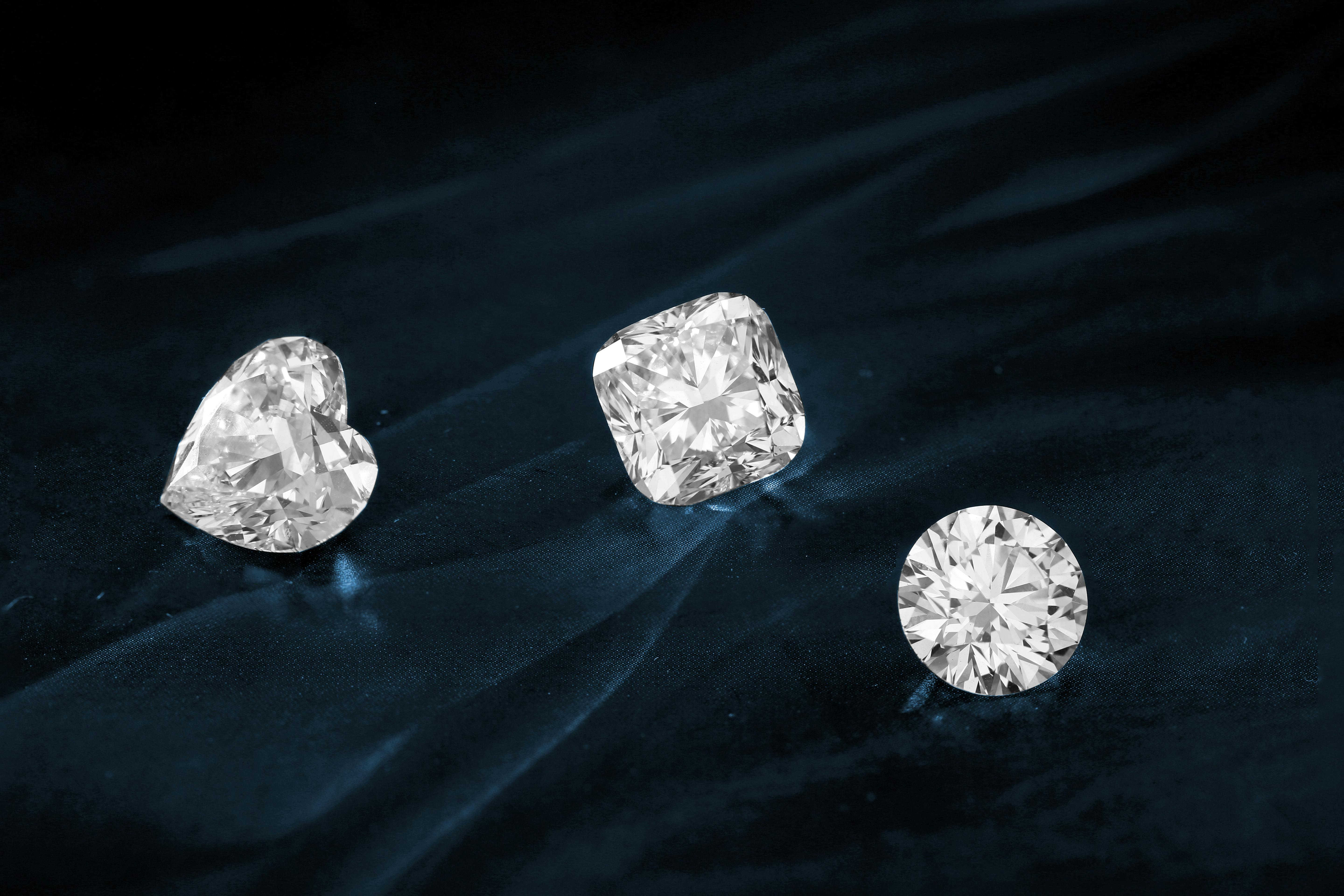 Round Brilliant, Heart and Cushion cut loose diamonds sparkle on a dark, navy blue velvet