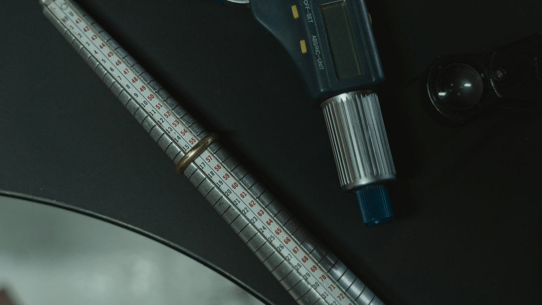 A ring sizer on a dark table alongside other sizing tools