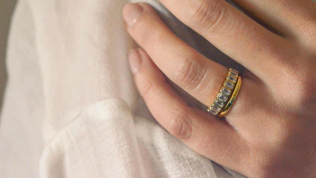 two wedding and worn on a finger, one plain and one with bezel set diamonds