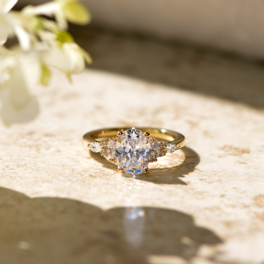 Gold ring with a diamond on a textured surface with flowers in the background