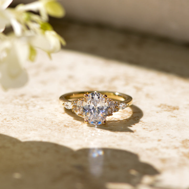 Gold ring with a diamond on a textured surface with flowers in the background