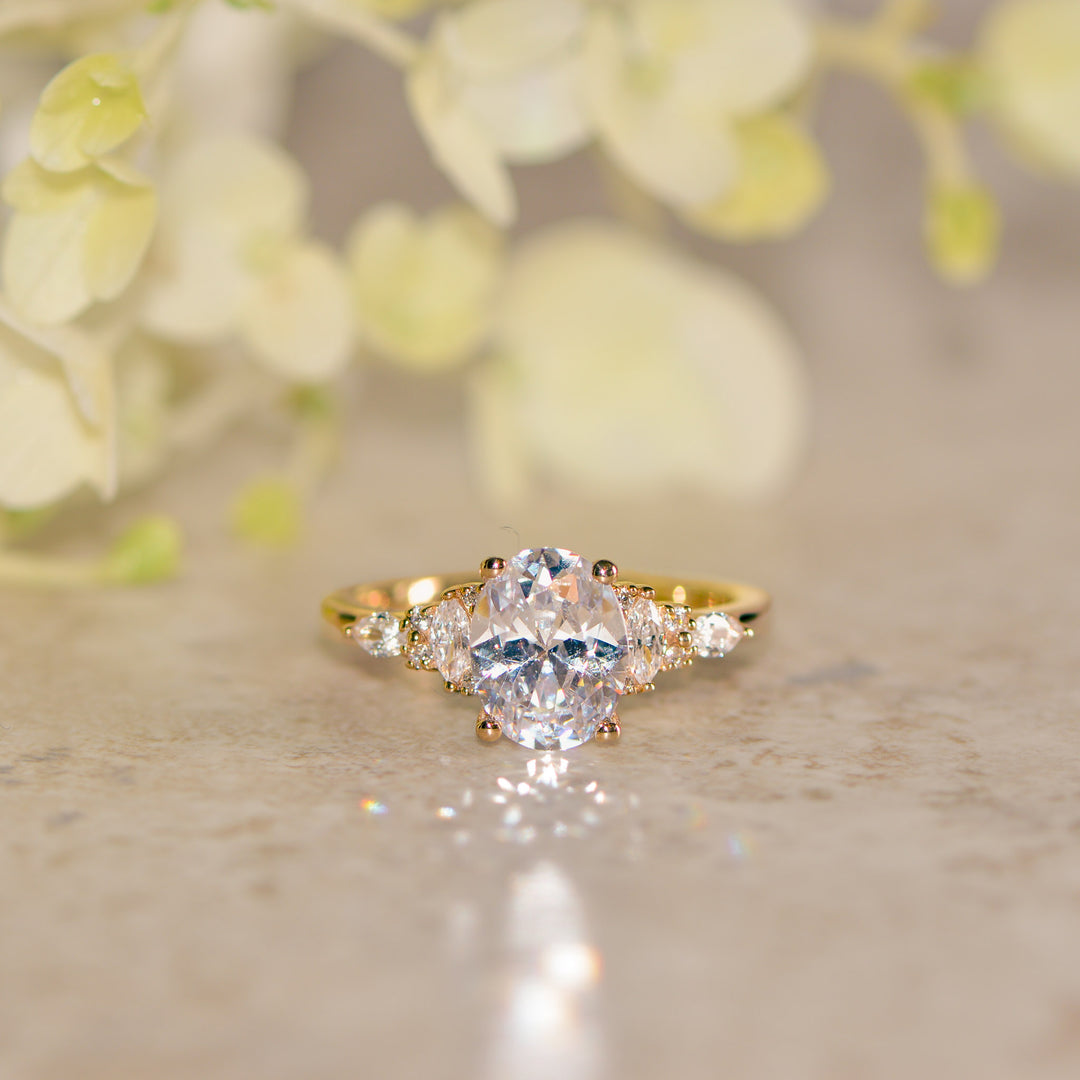 Gold oval cut ring with a diamond on a neutral background
