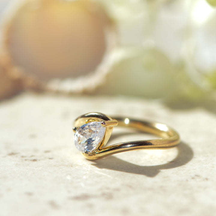 Gold ring set with a diamond on a marble background