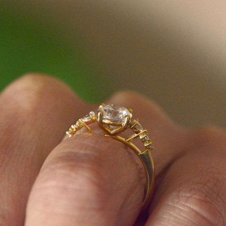 Gold ring with a diamond on a finger against a blurred background