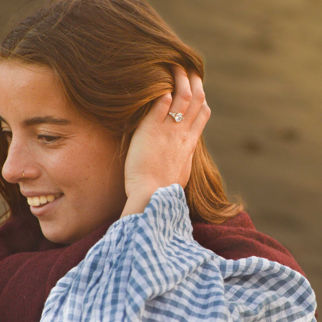 Woman with a ring on her finger touching another person's hair outdoors.