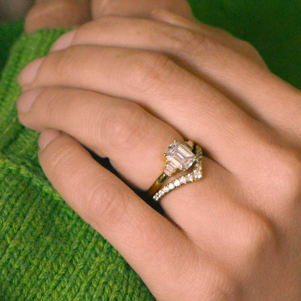 Close-up of a hand wearing a emerald cut diamond ring on a green textured background