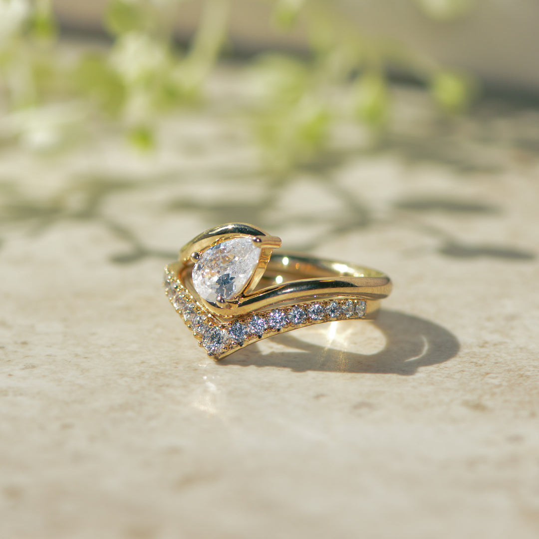 Gold ring with a pear-shaped diamond on a textured surface