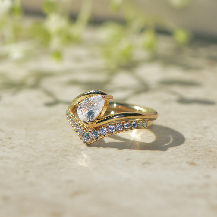 Gold ring with a pear-shaped diamond on a textured surface