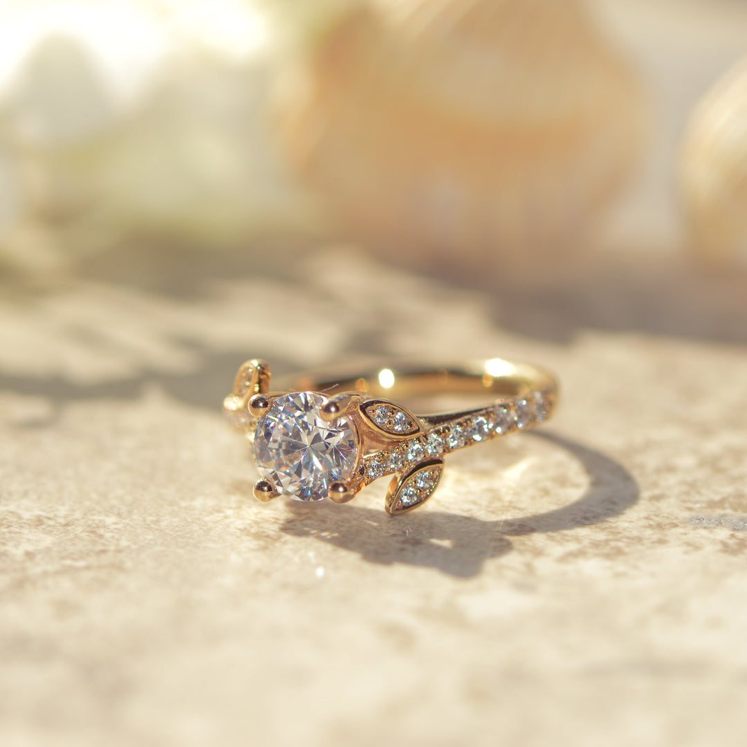 Gold pavé ring with a round brilliant cut diamond on a soft, blurred background
