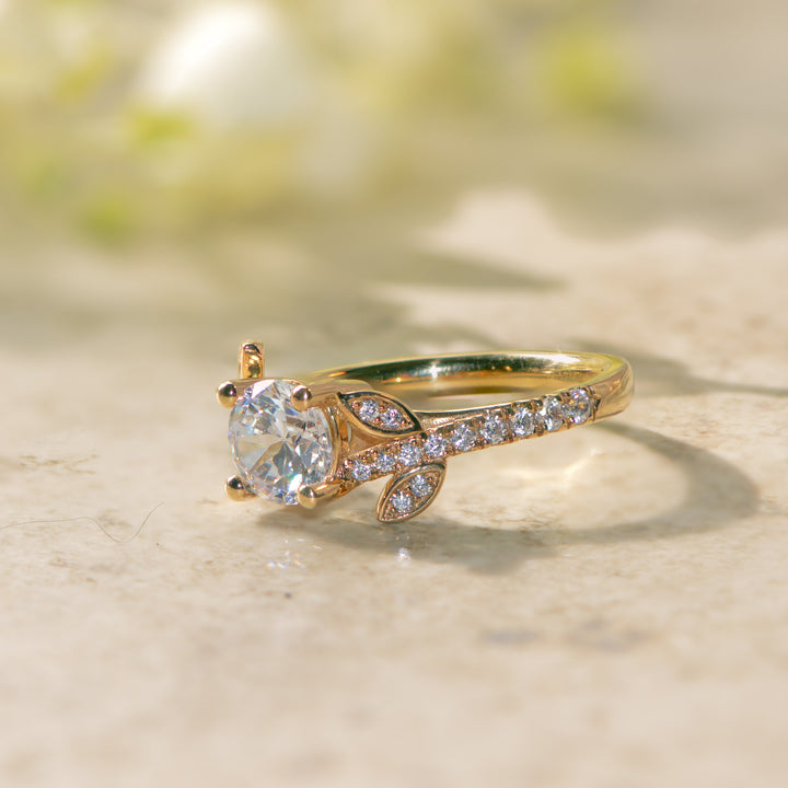 Gold shoulder set nature inspired ring with a diamond on a light background