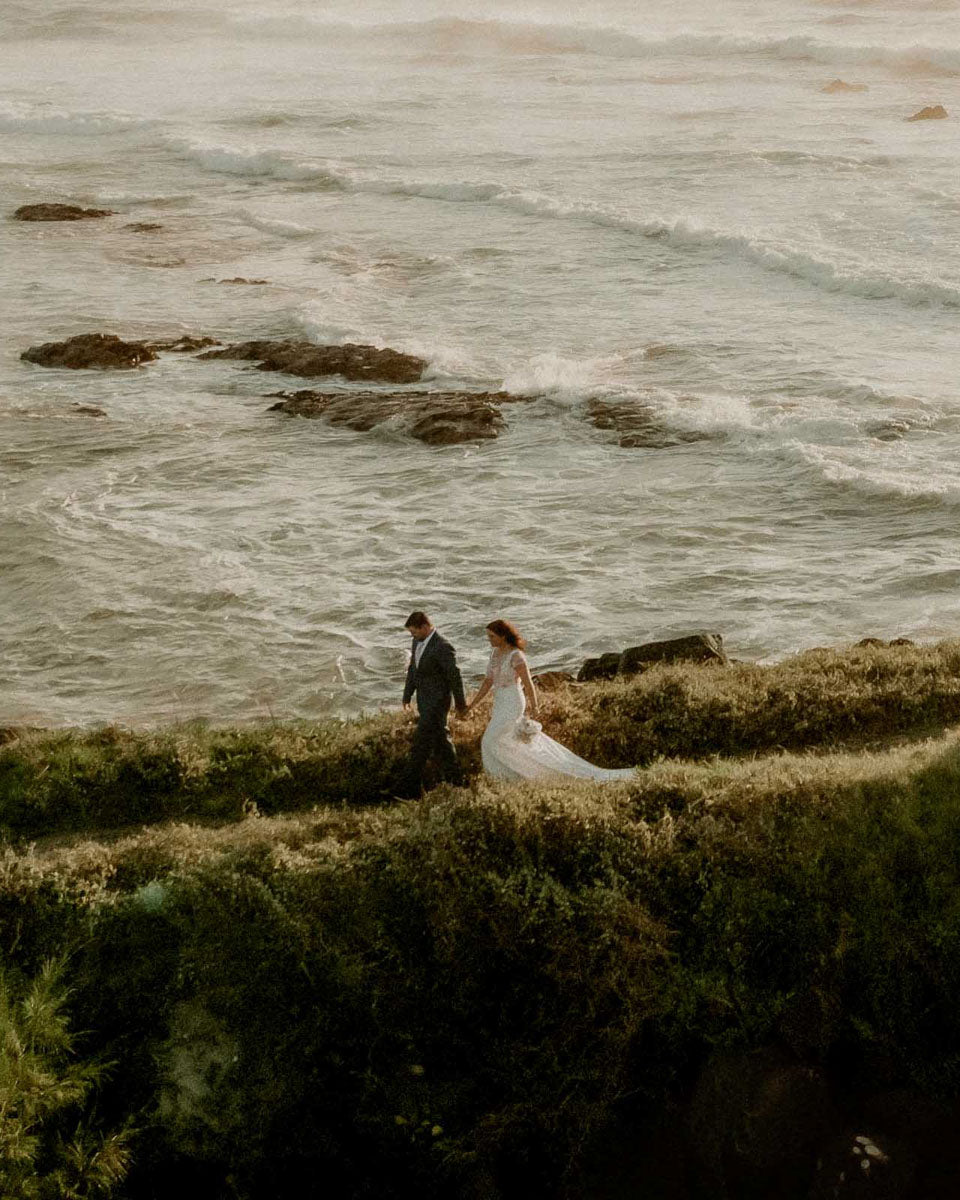 Couple walking across the cliffs after a Cornwall Beach Wedding 
