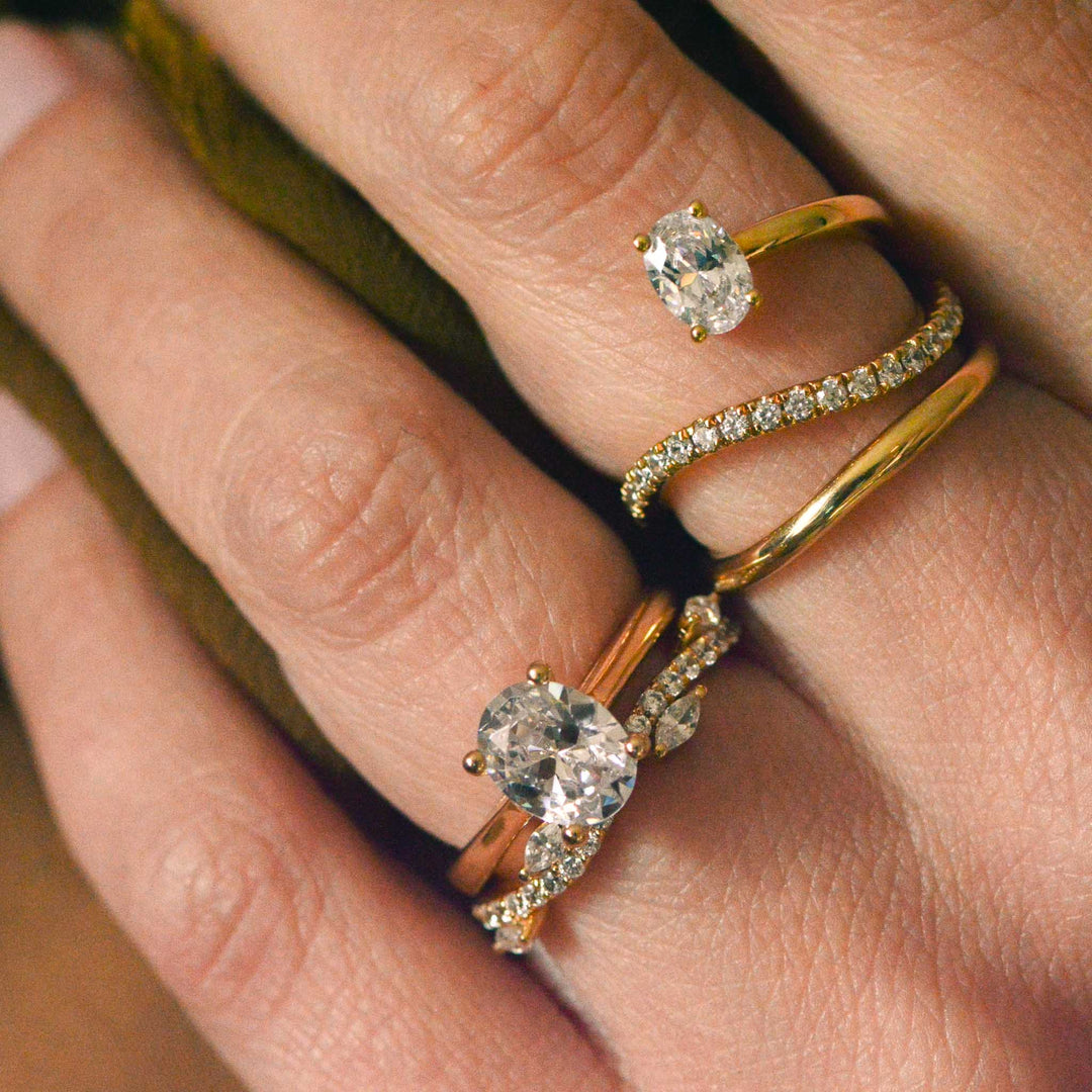 Close up of a collection of gold, diamond set bands worn on the hand