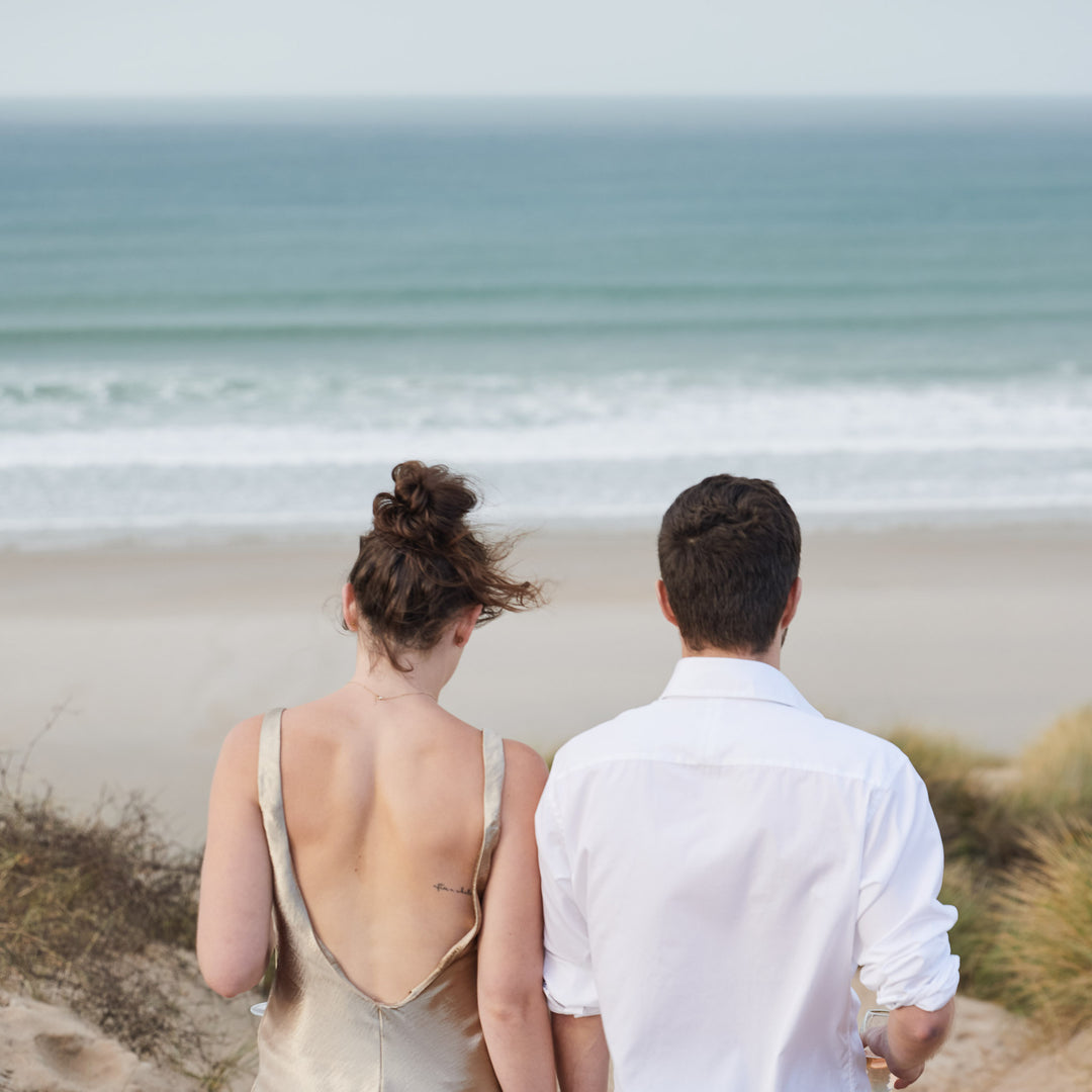 Couple at the beach walking towards the ocean after getting engagement at one of Cornwall's most popular beaches