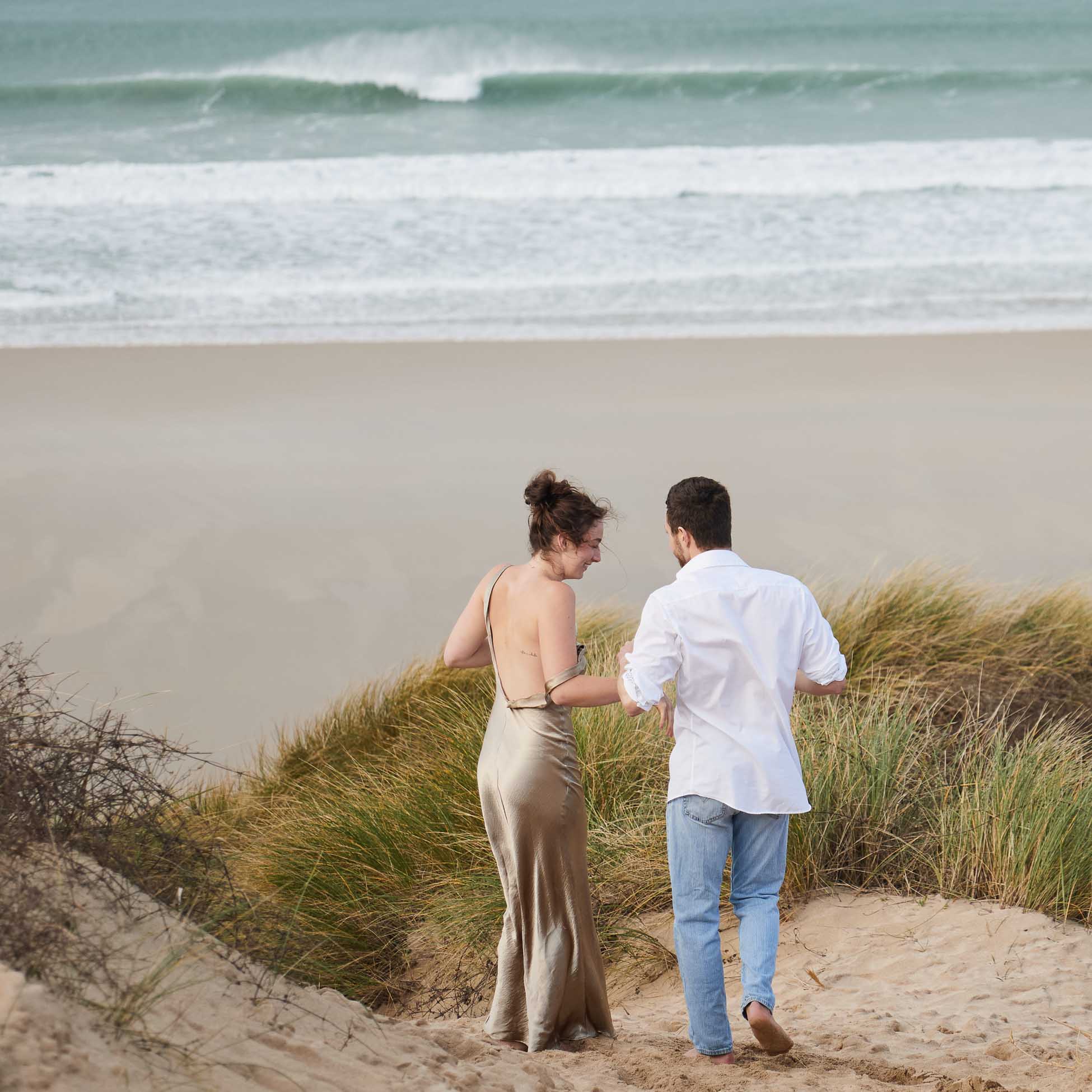 Couple walking along a sandy path by the ocean