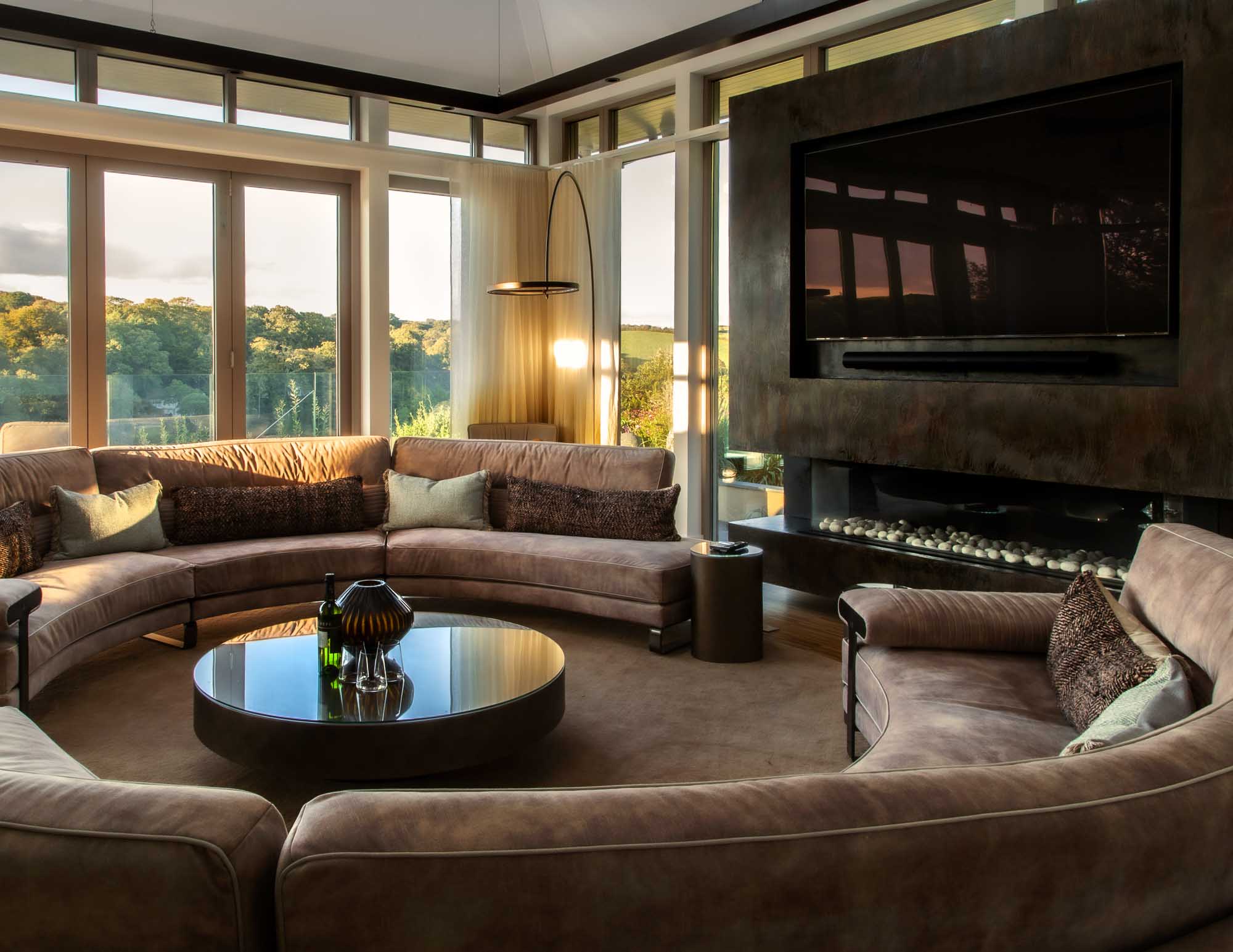 Modern living room with a conversation pit, round coffee table, and large windows.