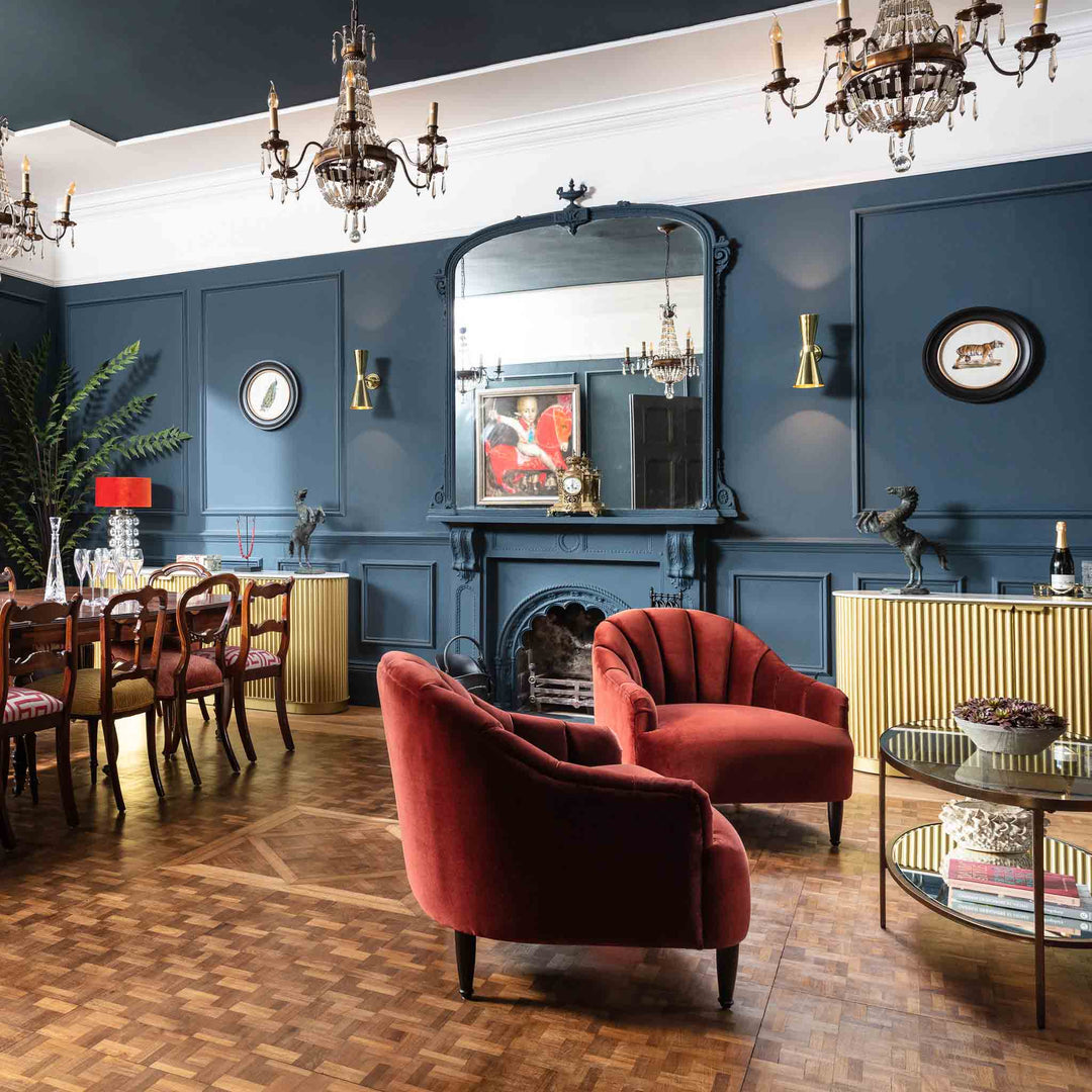 Luxurious living room with red chairs, a fireplace, and elegant decor.