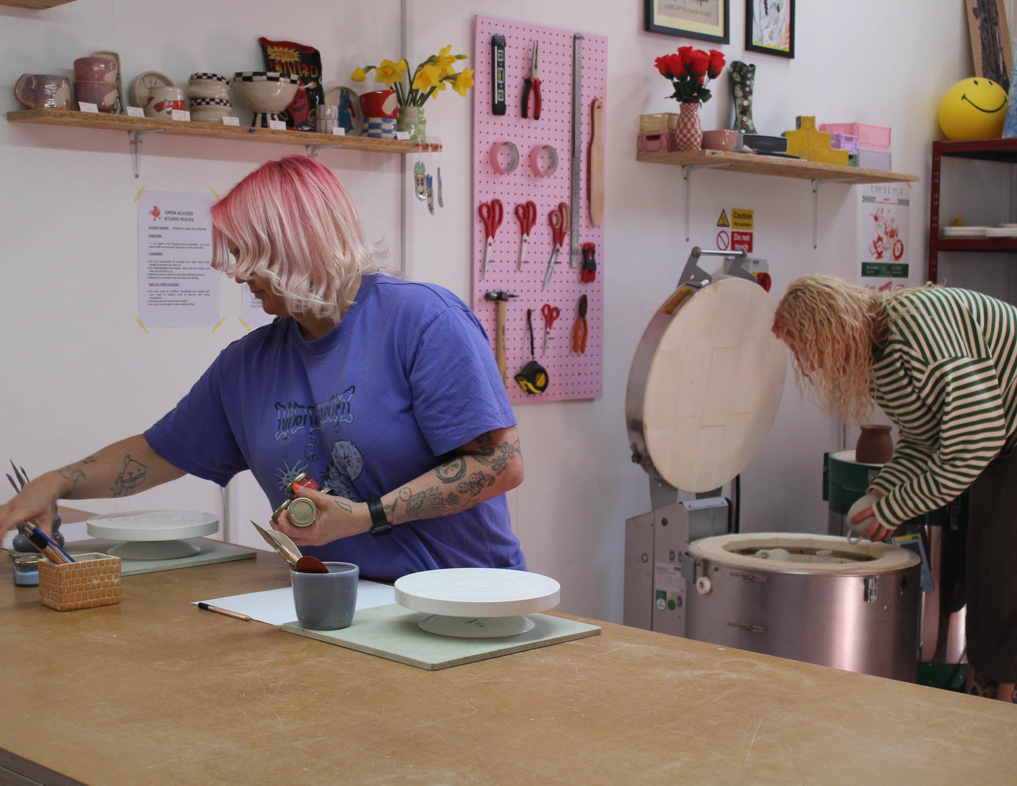 Two people working in a Cornish pottery studio loading a kiln with handmade ceramics.