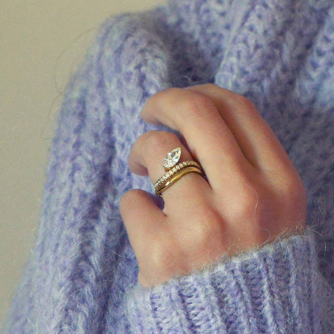 Close up of a hand wearing a custom diamond ring with a purple sweater background