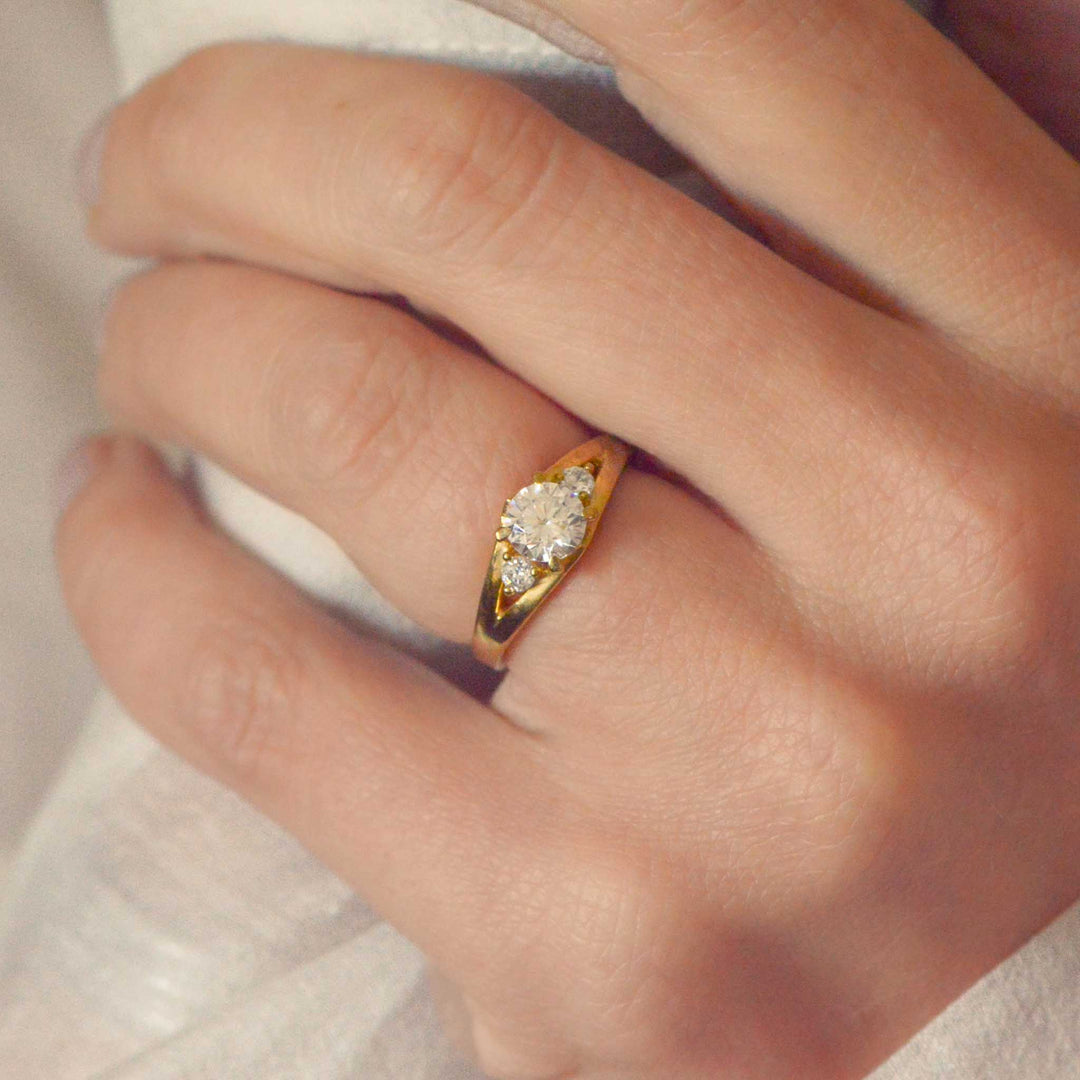 Gold three stone  ring with round diamonds on a person's finger