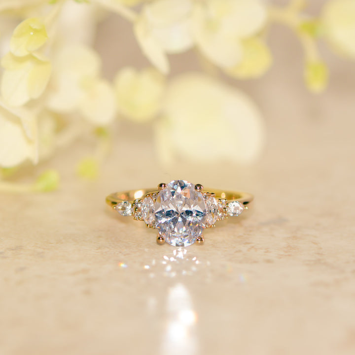 Gold ring with a large diamond and smaller stones on a soft, blurred background