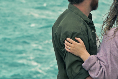 Person embracing another person by a body of water