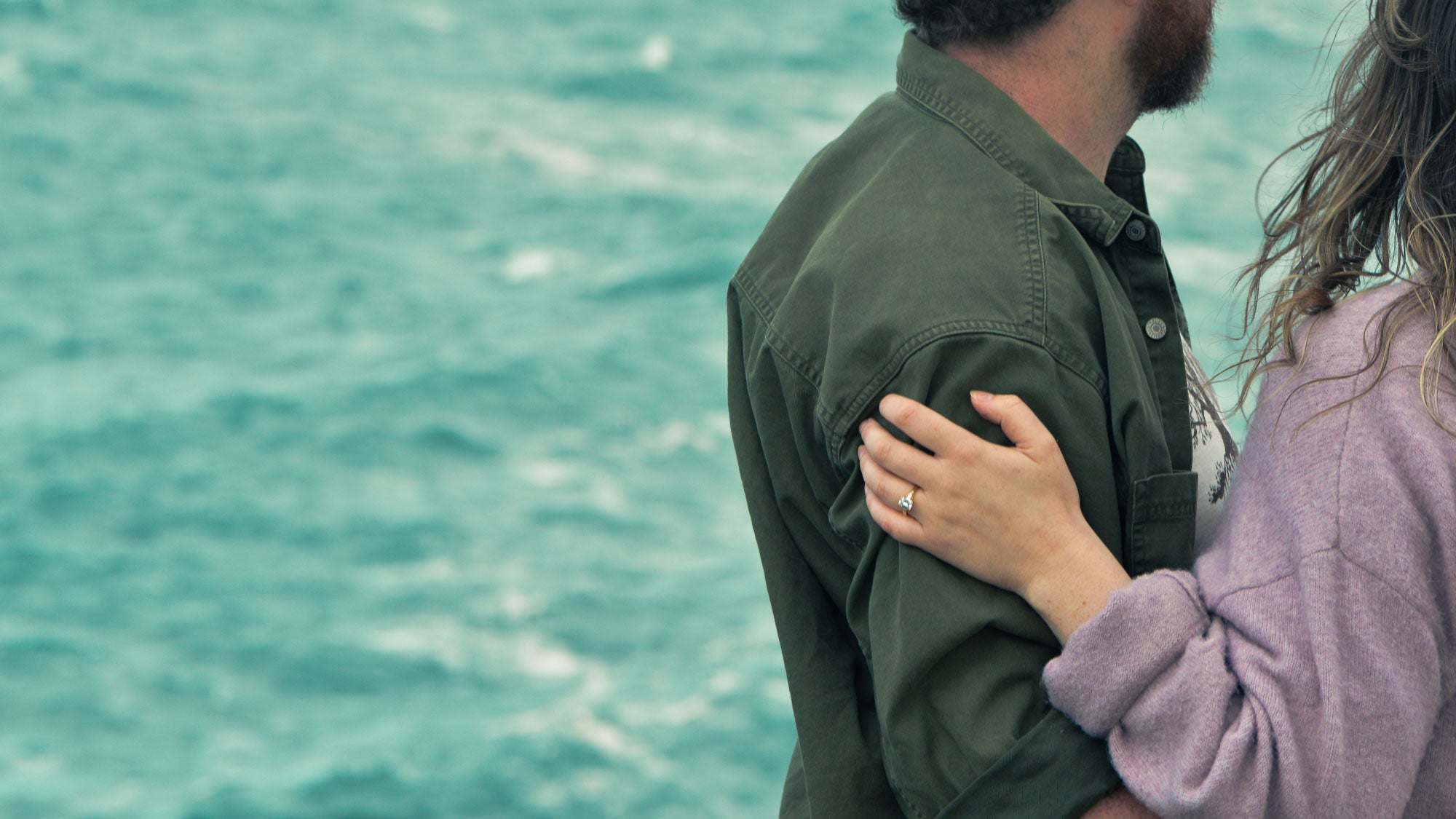 Two people embracing with a blurred ocean background