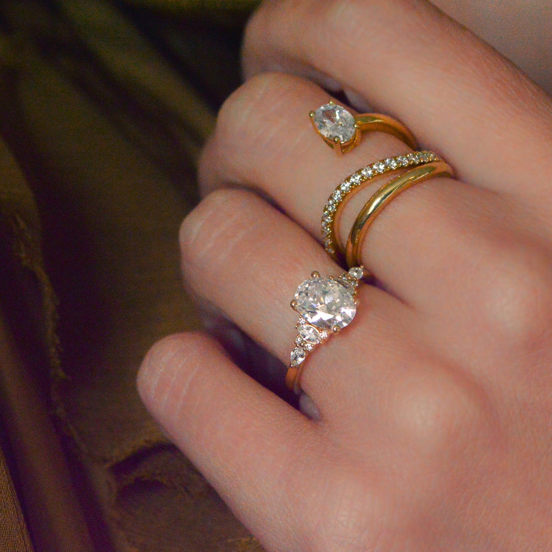 Close-up of a hand wearing two gold rings with diamond accents.