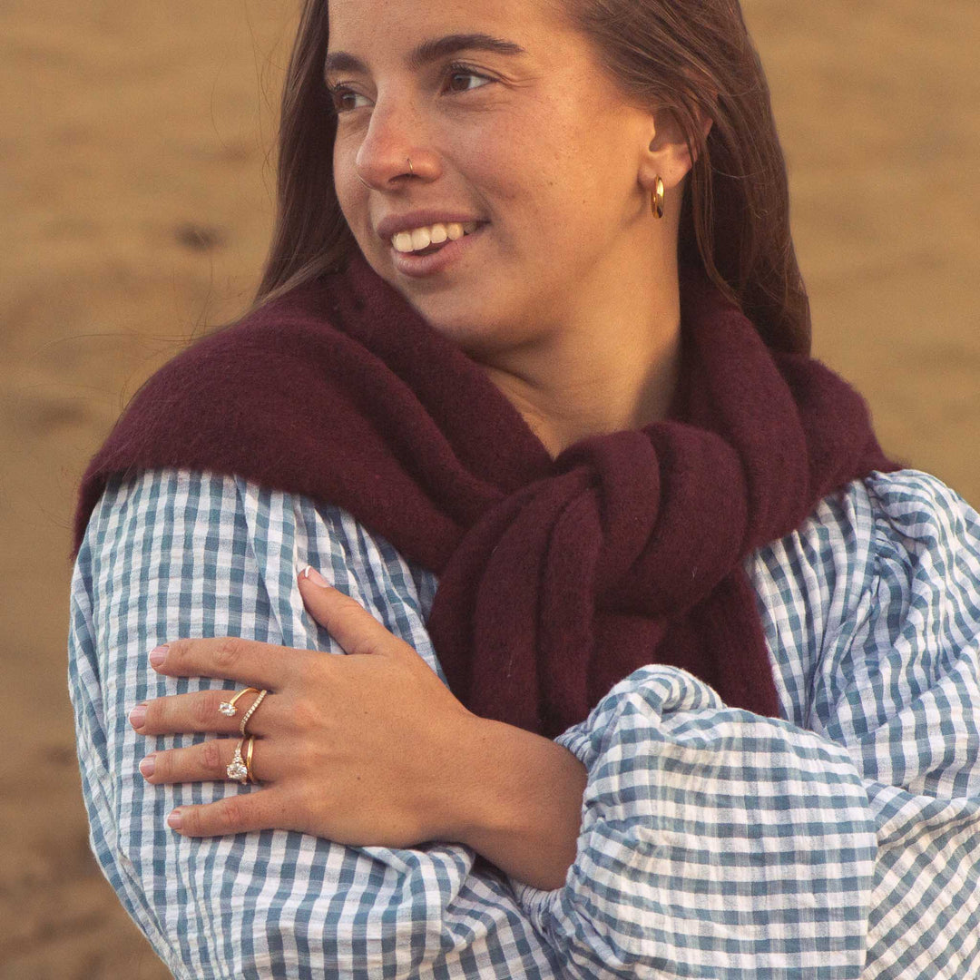 Woman wearing a maroon scarf and checkered shirt against a blurred background