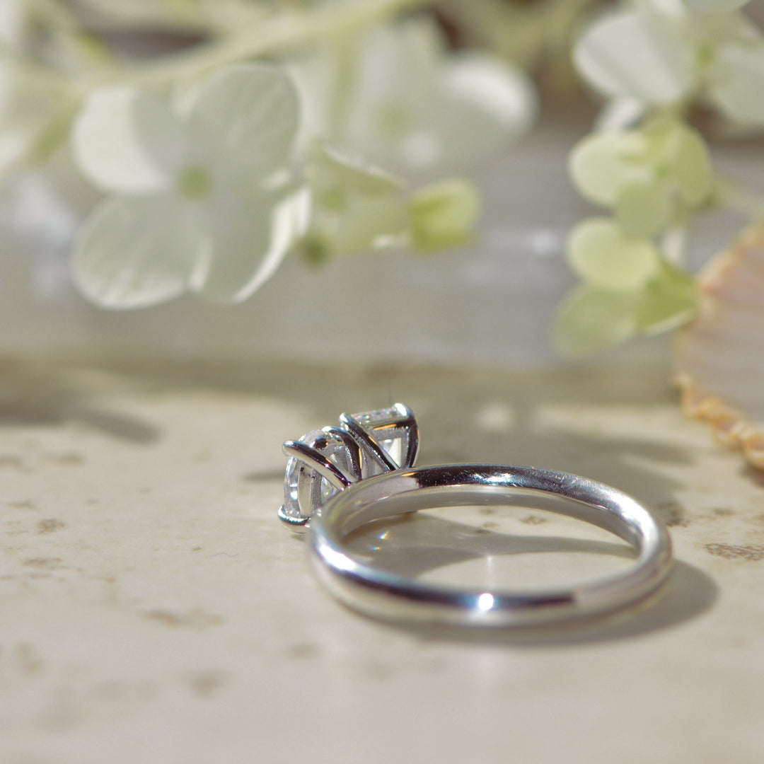Platinum two stone engagement ring with diamonds on a light background