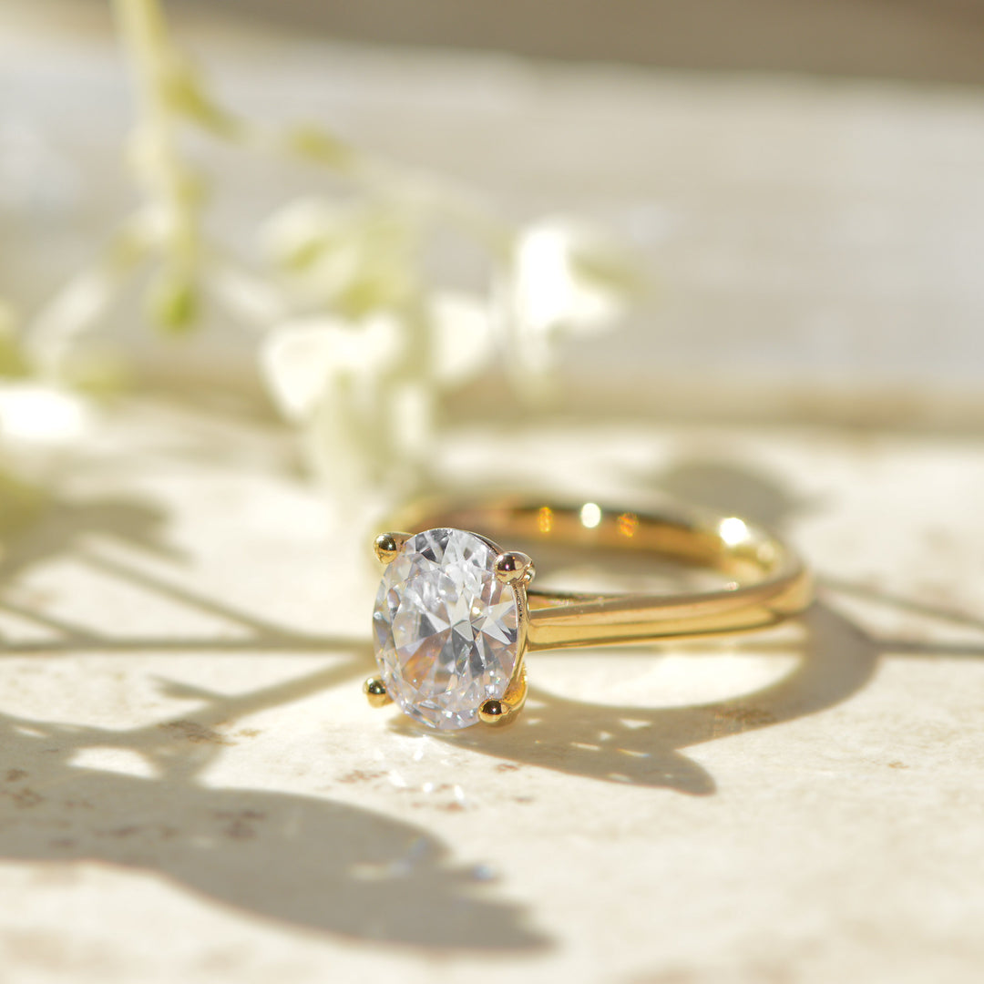 Gold ring with a large oval cut diamond on a light background