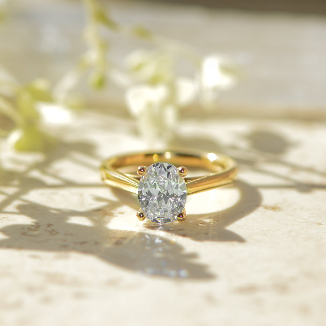 Oval Cut engagement ring in gold set with a diamond on a light background