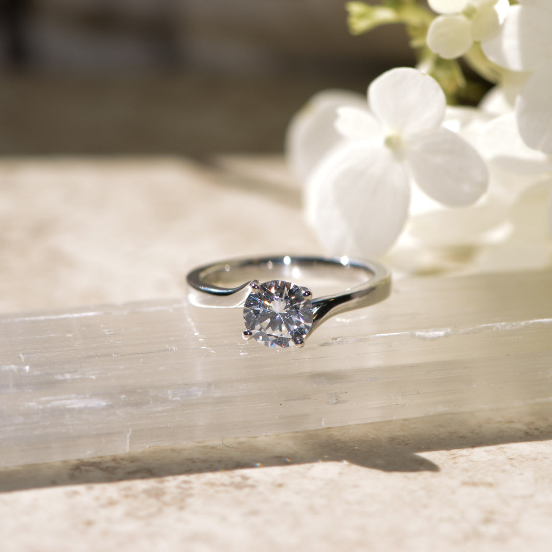 Diamond solitaire ring on marble with white flowers in the background
