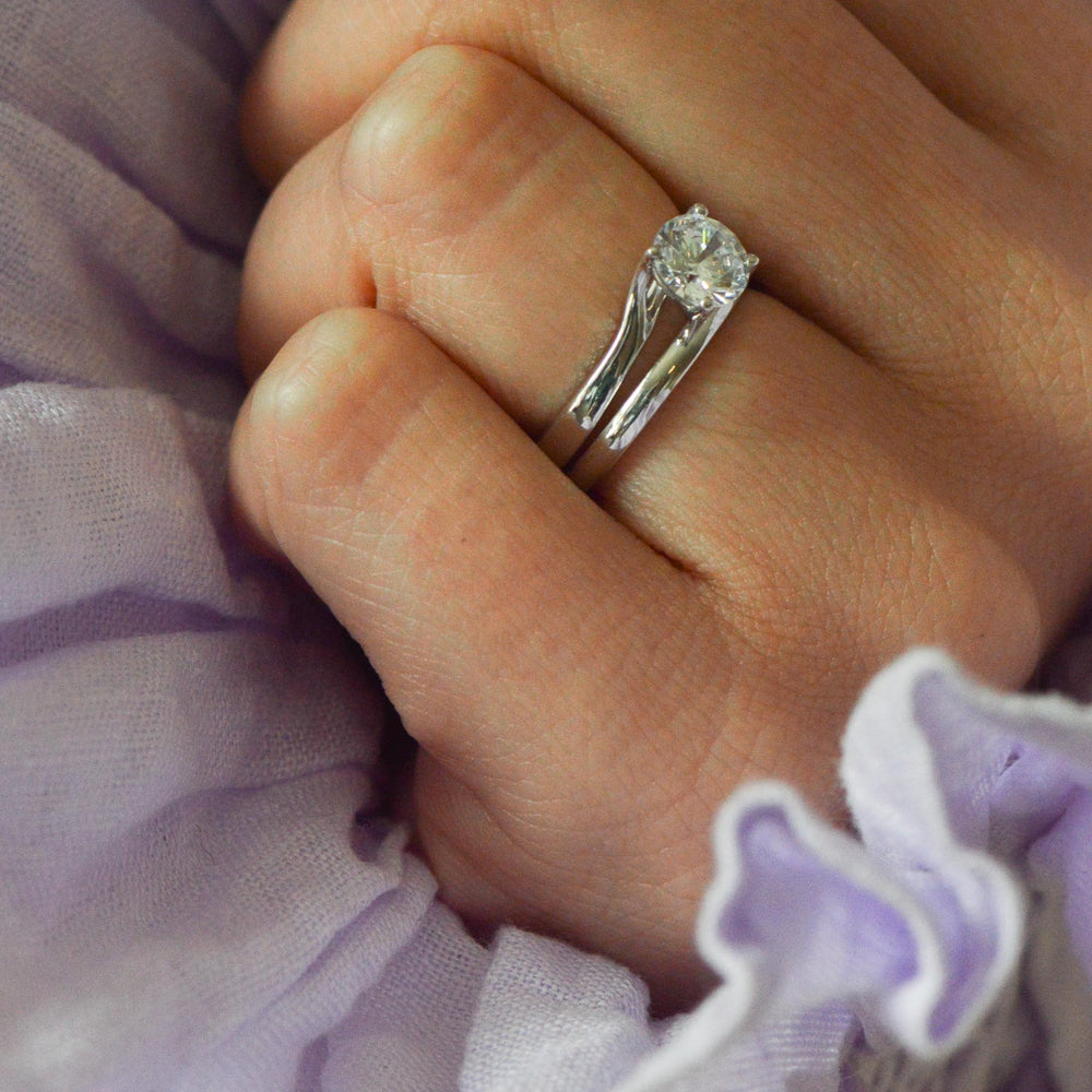 Close up of a round cut diamond engagement ring worn on the hand with a classic platinum wedding band