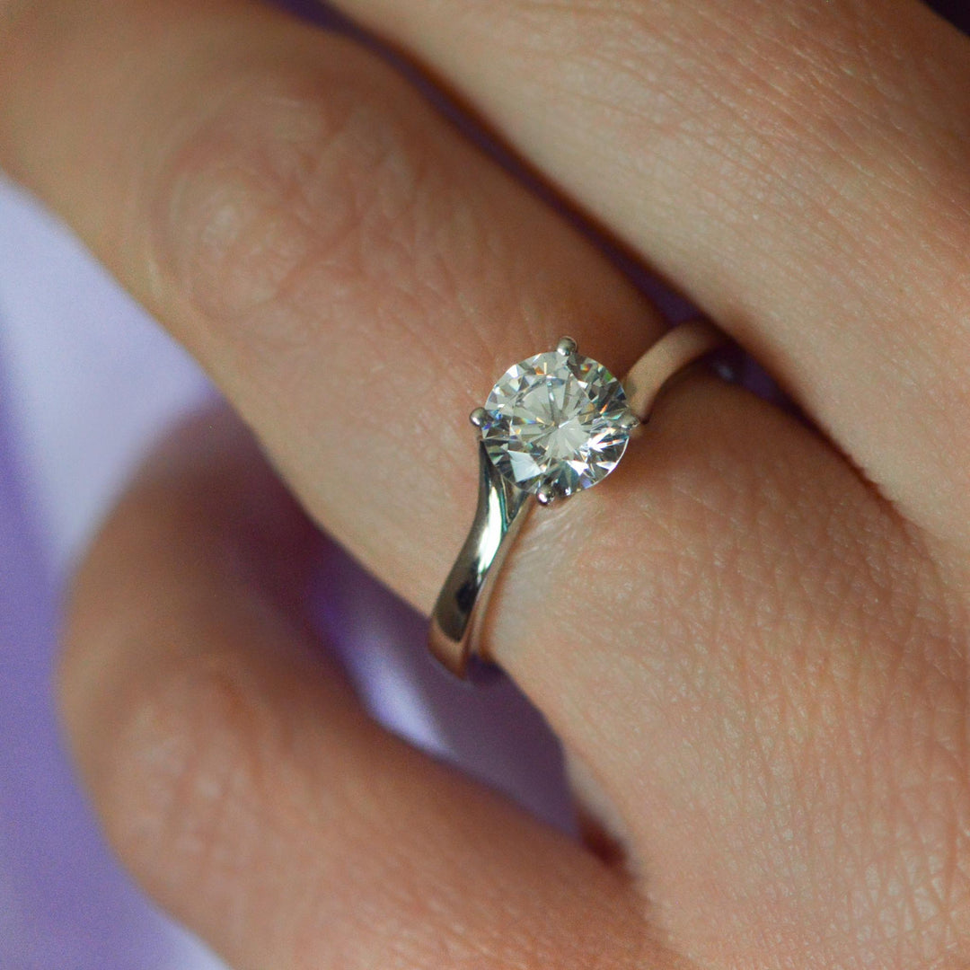 Close up of a round brilliant cut solitaire engagement ring worn on the hand