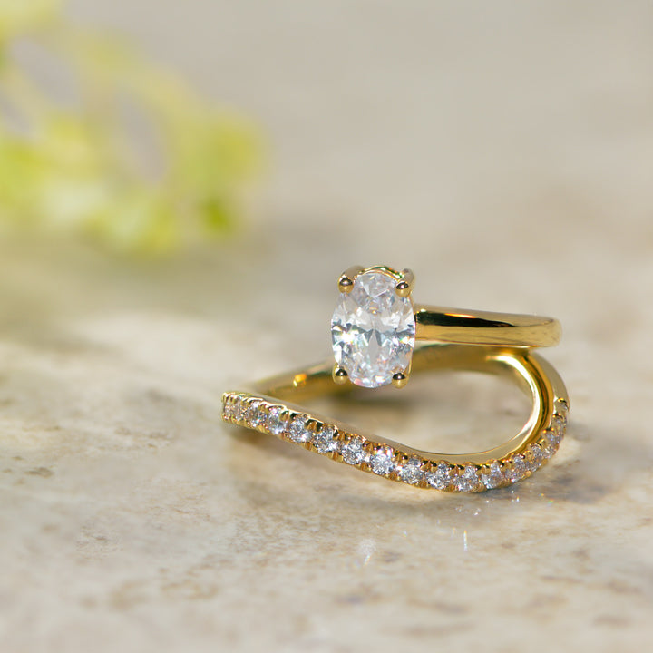 Gold oval cut ring with diamond pavé on a marble surface