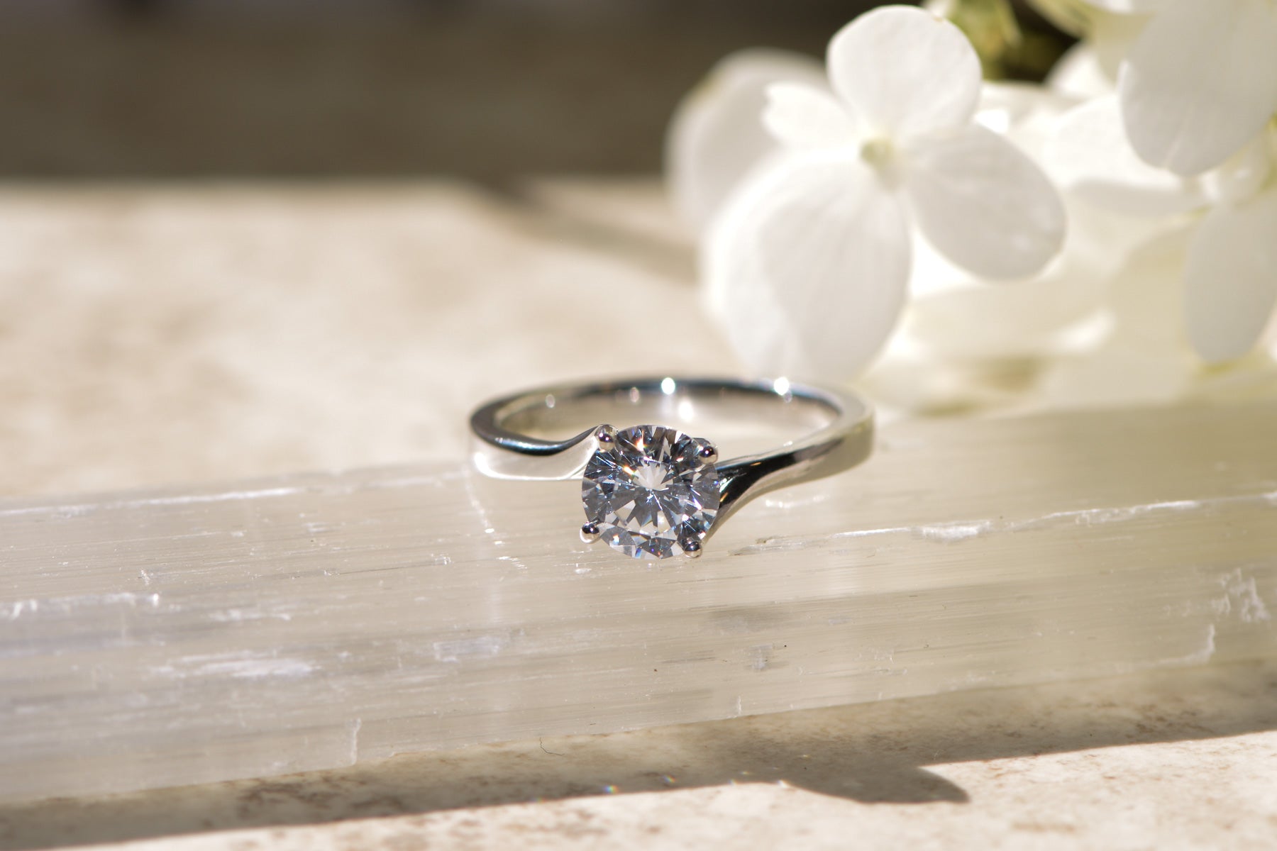 Platinum diamond engagement ring on a crystal surface with a blurred background
