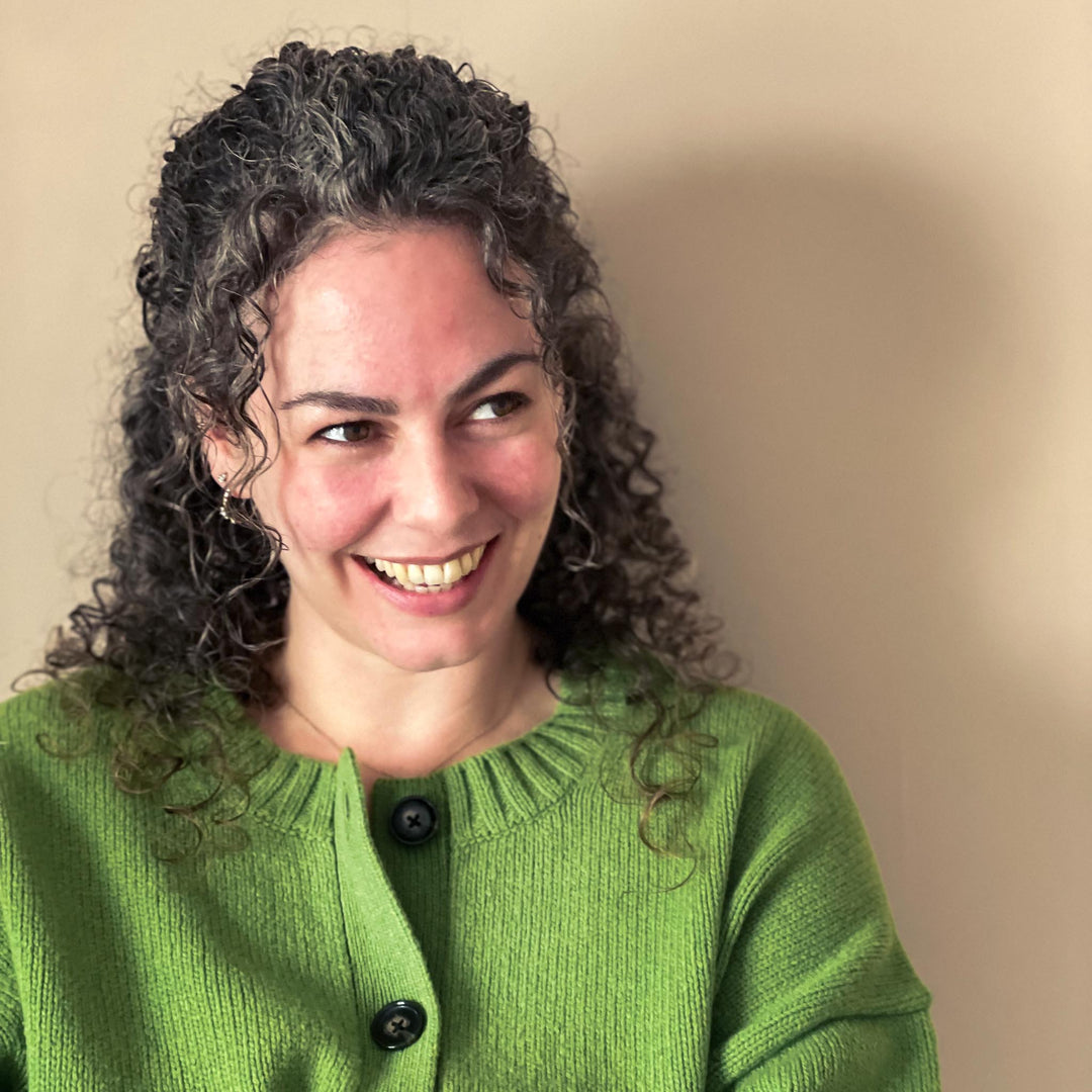 Woman wearing a green sweater against a beige background