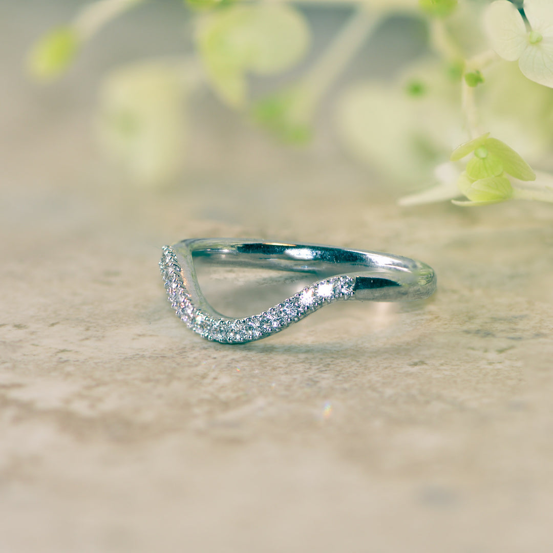 Pavé set dipped wedding band with diamonds on a light background