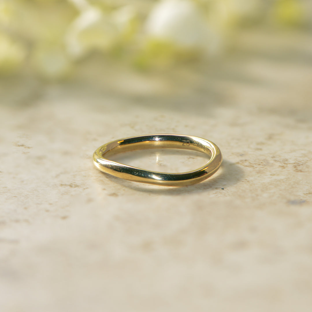 Gold ring on a marble surface with a blurred floral background