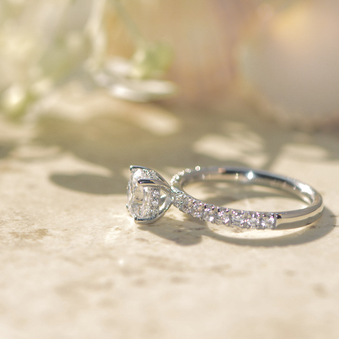 Platinum pavé engagement ring with a round brilliant cut diamond on a marble surface
