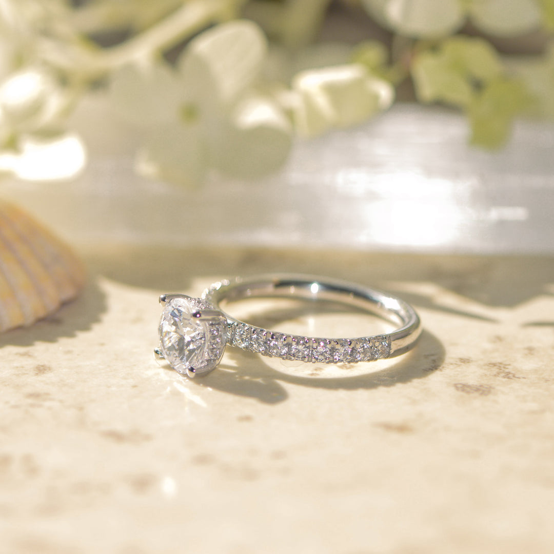 Platinum shoulder set ring with a large round cut diamond on a light background
